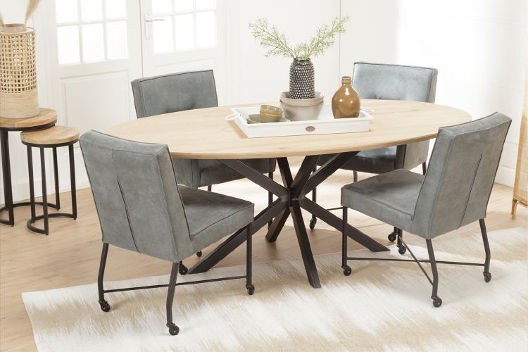 Blauwe eetkamerstoelen met wieltjes aan een ovale eettafel